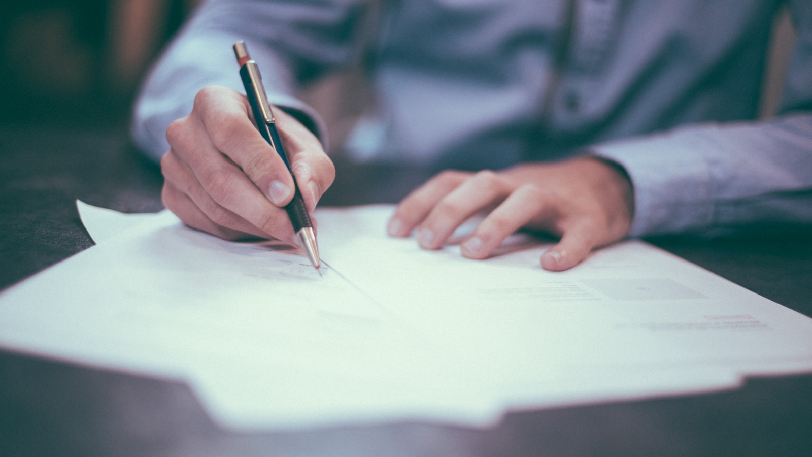 Signing closing documents with a pen at a desk